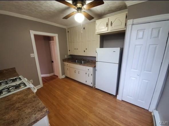 kitchen with white cabinets, white refrigerator, ornamental molding, light hardwood / wood-style floors, and baseboard heating