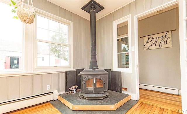 room details featuring baseboard heating, hardwood / wood-style flooring, and a wood stove