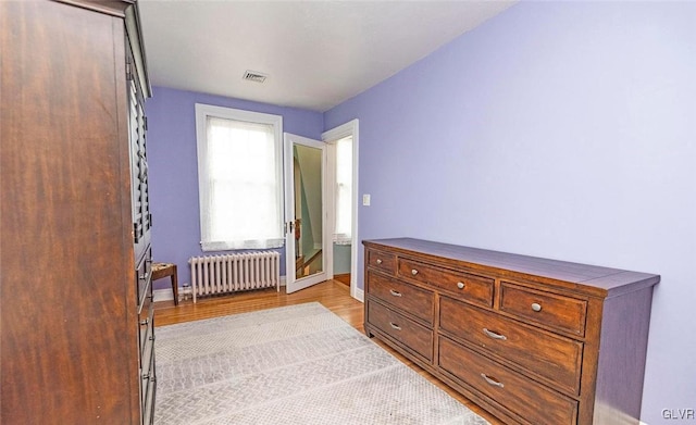 bedroom with radiator and light wood-type flooring