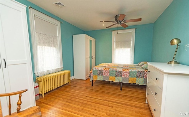 bedroom with radiator heating unit, ceiling fan, and light wood-type flooring