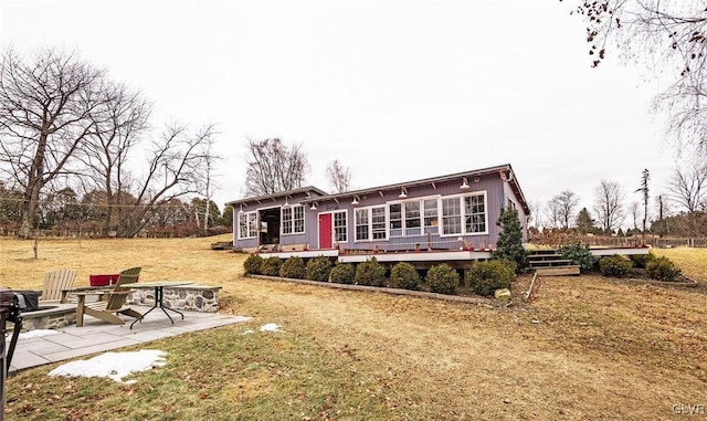 rear view of property with a patio, a yard, a wooden deck, and an outdoor fire pit