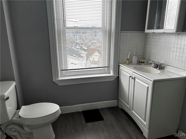 bathroom featuring vanity, toilet, wood-type flooring, and backsplash