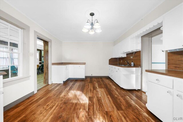 kitchen featuring dark wood-type flooring, sink, an inviting chandelier, pendant lighting, and white cabinets