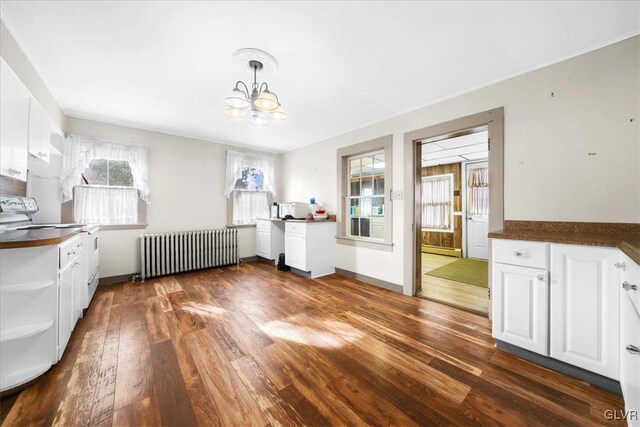 unfurnished dining area featuring dark wood-type flooring, a baseboard radiator, radiator heating unit, and a notable chandelier