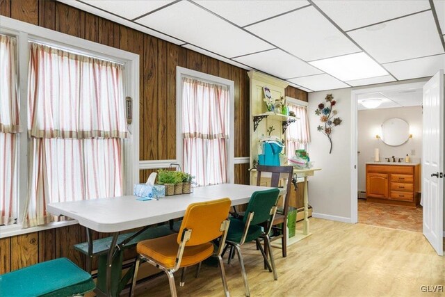 dining space with sink, wooden walls, and a baseboard radiator