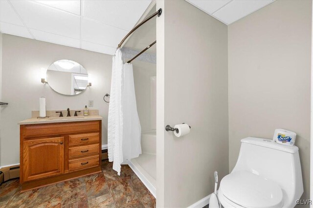 bathroom with toilet, a paneled ceiling, vanity, curtained shower, and a baseboard heating unit