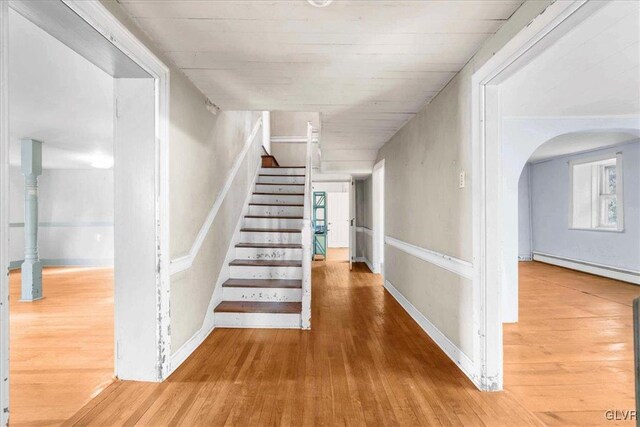 staircase featuring baseboard heating and hardwood / wood-style floors