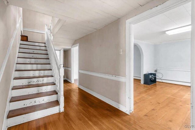 stairs featuring hardwood / wood-style floors and a baseboard heating unit