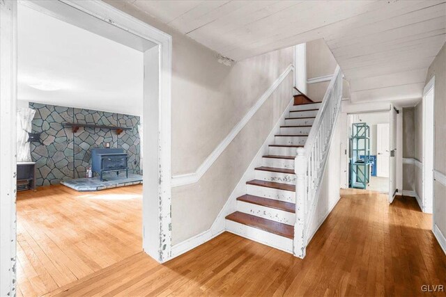 staircase featuring wood-type flooring and a wood stove