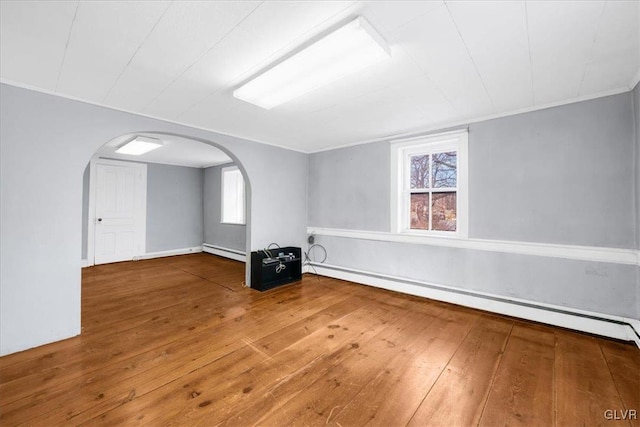 empty room with wood-type flooring, a healthy amount of sunlight, and baseboard heating