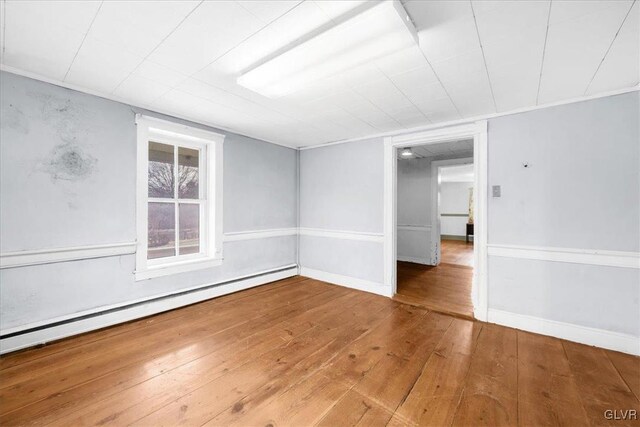 unfurnished room featuring hardwood / wood-style flooring and a baseboard radiator