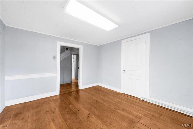 unfurnished room with ornamental molding and wood-type flooring