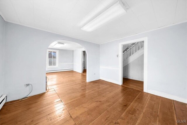 unfurnished room with a baseboard heating unit, crown molding, and wood-type flooring