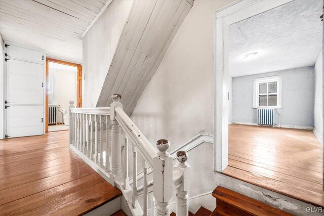 stairs featuring hardwood / wood-style flooring and radiator heating unit