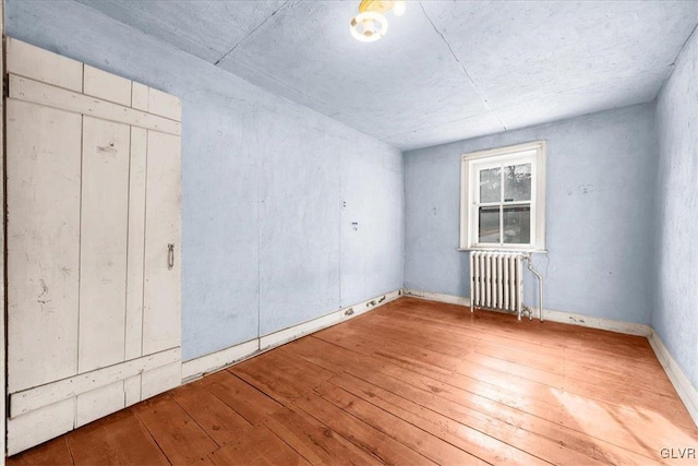 spare room with radiator and hardwood / wood-style flooring