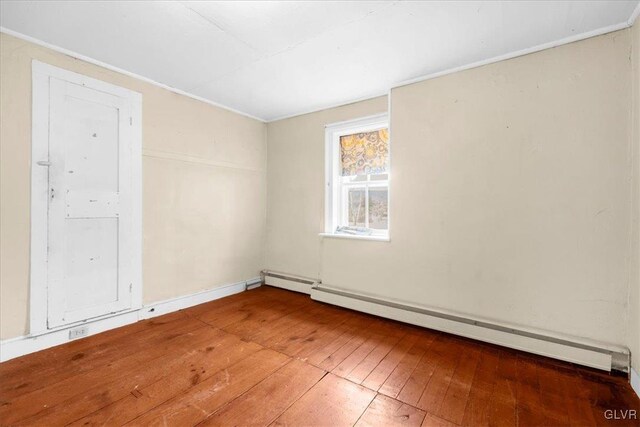 spare room featuring hardwood / wood-style flooring and a baseboard heating unit