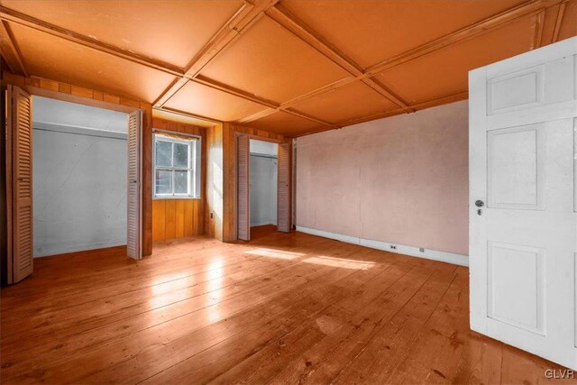 unfurnished bedroom with light hardwood / wood-style flooring and two closets