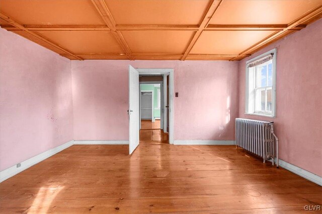 spare room featuring hardwood / wood-style flooring, coffered ceiling, and radiator