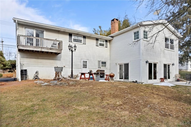 back of house featuring a balcony, a patio, and a lawn