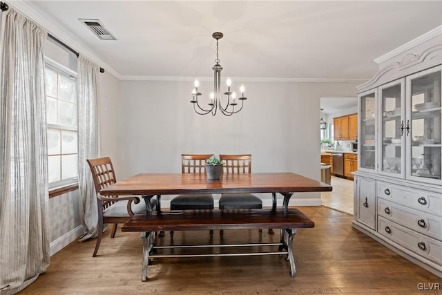 dining room with ornamental molding, a chandelier, and light hardwood / wood-style floors