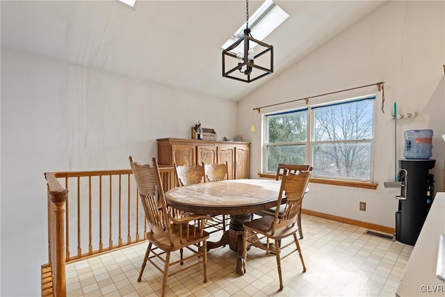 dining space with vaulted ceiling with skylight and a chandelier