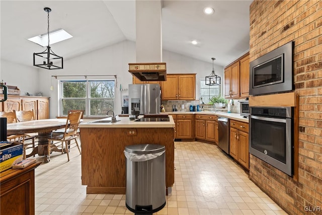 kitchen with decorative light fixtures, lofted ceiling, sink, a kitchen island with sink, and stainless steel appliances