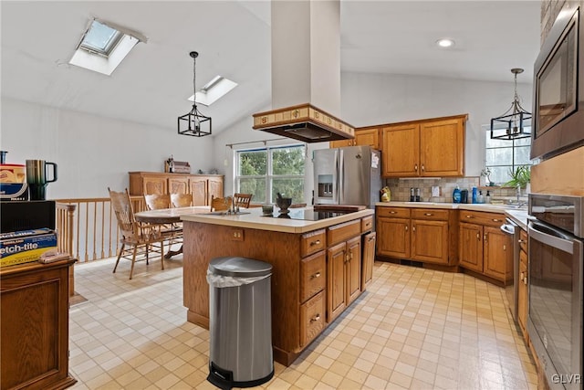 kitchen with appliances with stainless steel finishes, a kitchen island, a skylight, decorative light fixtures, and island exhaust hood