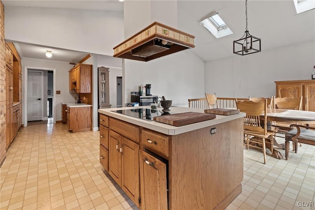 kitchen featuring premium range hood, pendant lighting, high vaulted ceiling, a skylight, and a center island