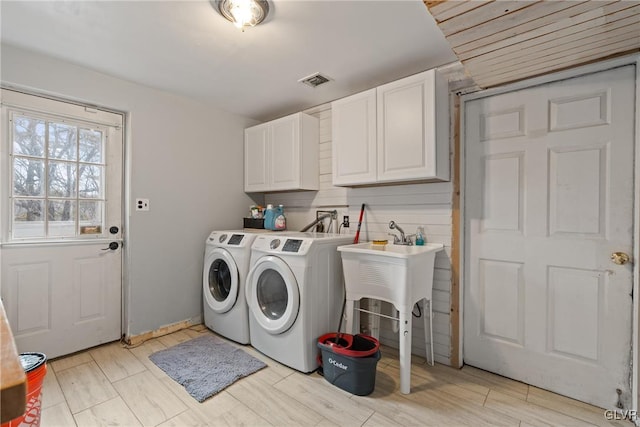 clothes washing area featuring cabinets, separate washer and dryer, and light hardwood / wood-style floors