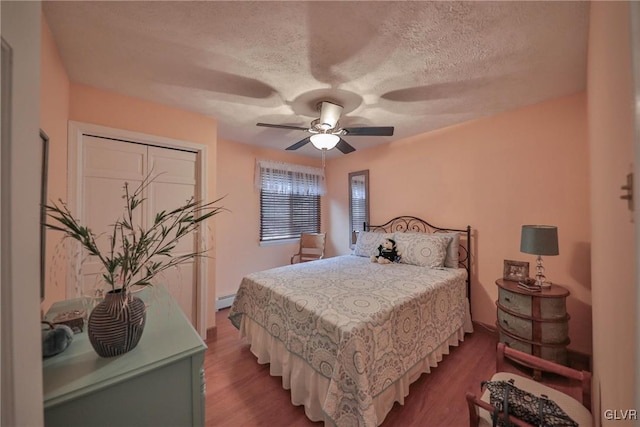 bedroom featuring hardwood / wood-style floors, ceiling fan, a textured ceiling, and baseboard heating