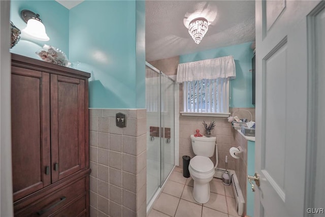 bathroom with tile patterned flooring, tile walls, a textured ceiling, and toilet