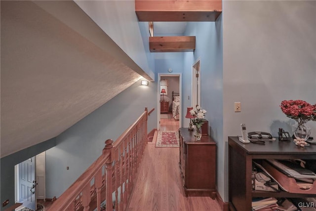 corridor featuring beamed ceiling and light hardwood / wood-style floors