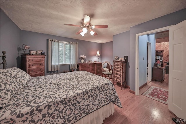 bedroom with ceiling fan, a textured ceiling, and light hardwood / wood-style flooring