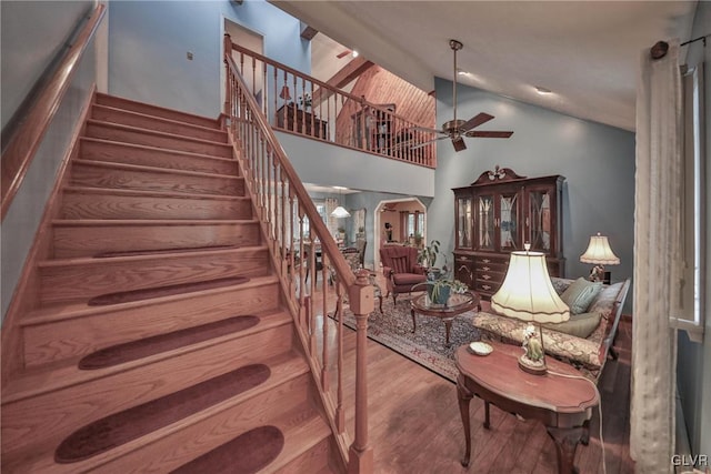 stairs featuring hardwood / wood-style flooring, high vaulted ceiling, and ceiling fan