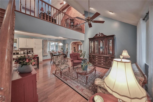 living room featuring ceiling fan, high vaulted ceiling, and light wood-type flooring