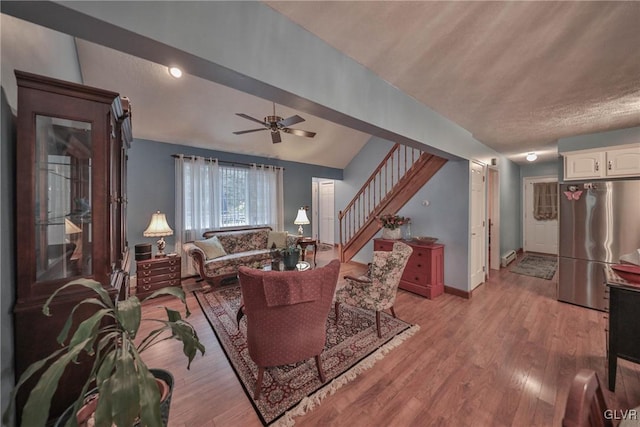 living room featuring ceiling fan, lofted ceiling, and light hardwood / wood-style floors