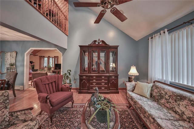 living room with ceiling fan, high vaulted ceiling, light wood-type flooring, and baseboard heating