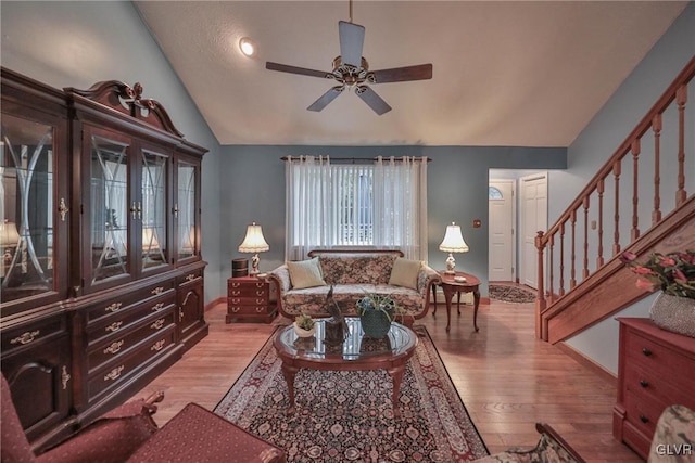 living room with vaulted ceiling, ceiling fan, and light wood-type flooring