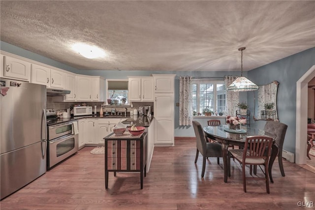 kitchen with pendant lighting, white cabinetry, plenty of natural light, and stainless steel appliances