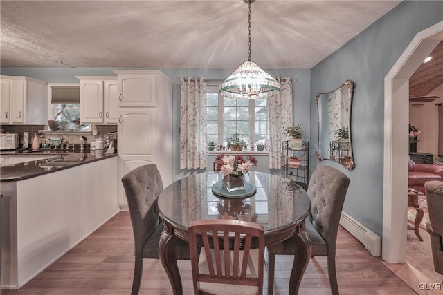 dining space featuring sink, dark wood-type flooring, a chandelier, and baseboard heating