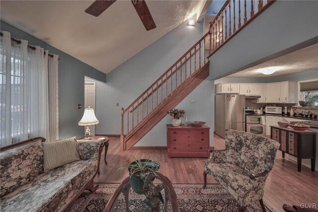 living room featuring high vaulted ceiling, light hardwood / wood-style floors, sink, and ceiling fan