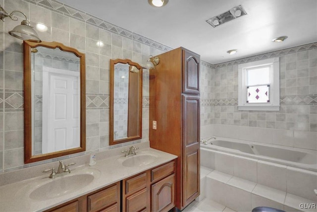 bathroom with tile patterned flooring, vanity, tiled tub, and tile walls