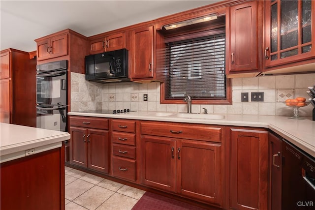 kitchen featuring tasteful backsplash, sink, light tile patterned floors, and black appliances