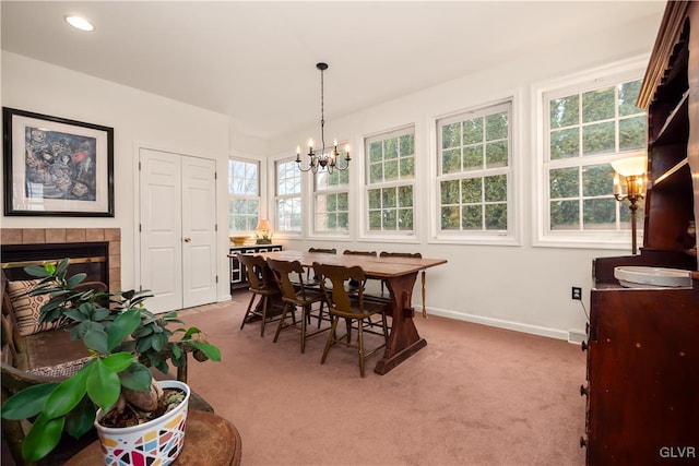 dining area with carpet floors, a tile fireplace, and a chandelier