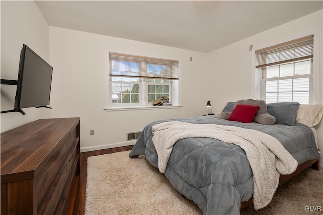 bedroom with multiple windows and hardwood / wood-style flooring