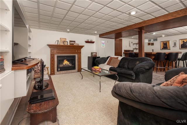 carpeted living room with a drop ceiling and indoor bar