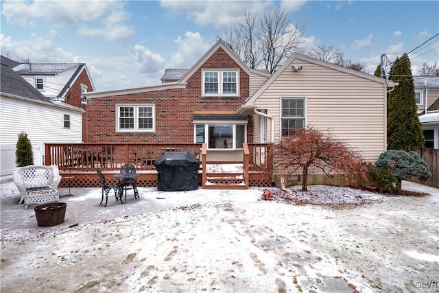 snow covered back of property featuring a wooden deck