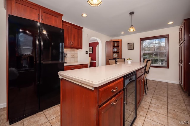 kitchen with black fridge, decorative light fixtures, a center island, light tile patterned floors, and decorative backsplash