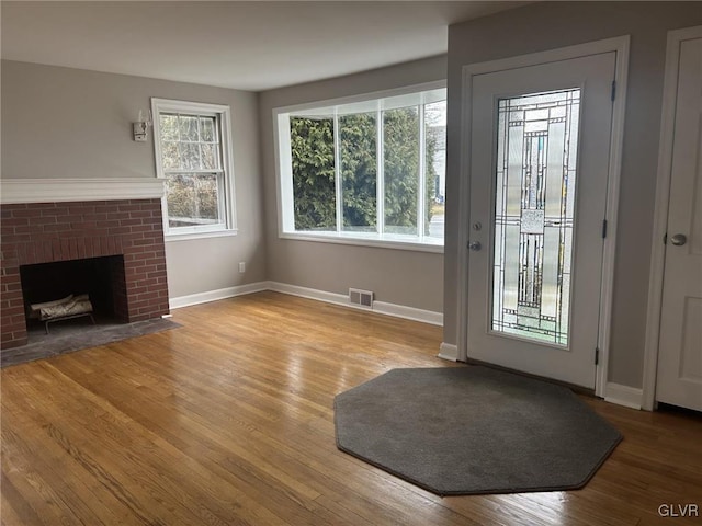 doorway to outside featuring a brick fireplace and light hardwood / wood-style floors