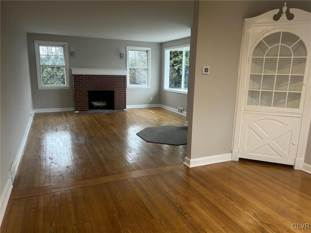 unfurnished living room with hardwood / wood-style flooring and a brick fireplace